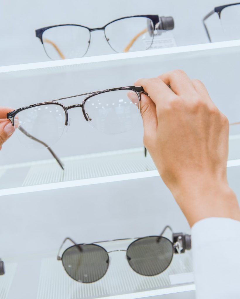 cropped view of doctor taking eyeglasses from shelf in ophthalmic shop
